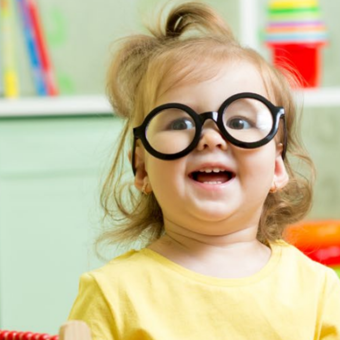 A toddler smiles as she plays with her toys